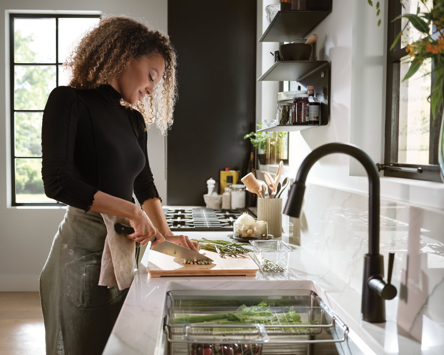 Woman cutting vegetables with Moen Riley Kitchen Faucet and Moen Luxe Chef Kitchen Sink